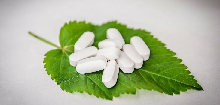 Tabletten auf grünem Blatt als Symbol für Hausmittel